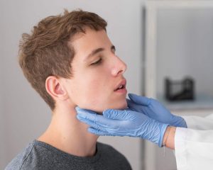 Médico sostiene el rostro de un joven y lo examina, el joven quiere realizarse la rinoplastia antes y después en Málaga