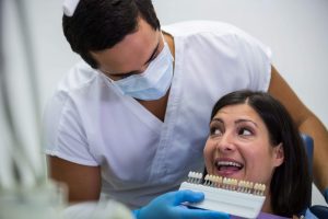 Doctor revisa en una cita de implantología avanzada el color de los implantes que más se acerca al color natural de los dientes de la paciente