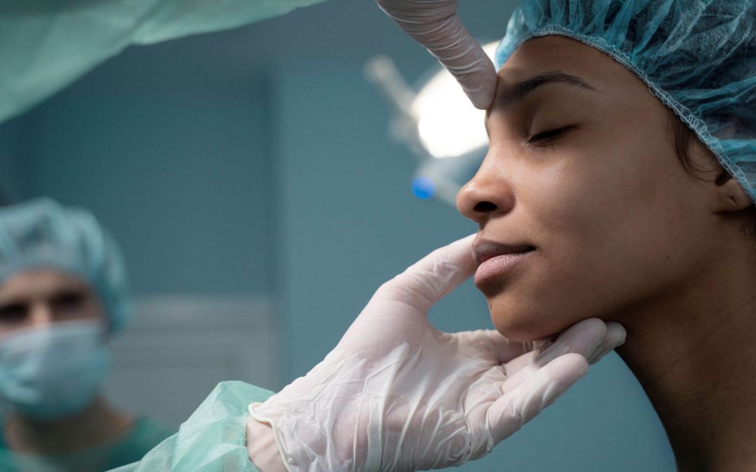Doctor revisa rostro de una paciente de rinoplastia antes y después, él sostiene su rostro mientras la examina